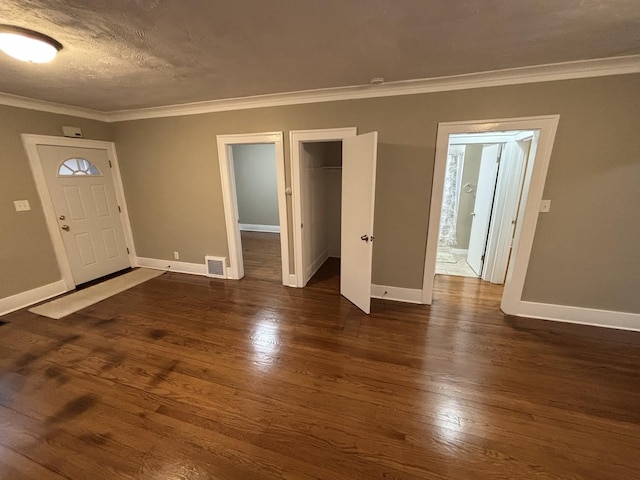 entryway with crown molding, dark wood-type flooring, and a textured ceiling