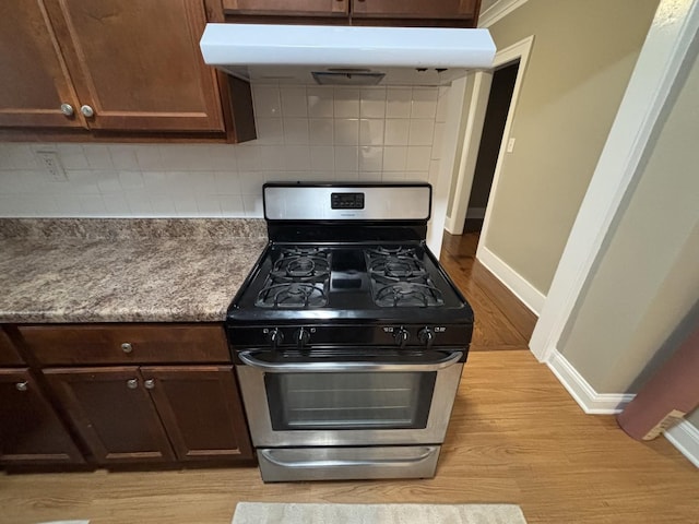 kitchen with decorative backsplash, light wood-type flooring, stainless steel gas stove, and dark brown cabinets