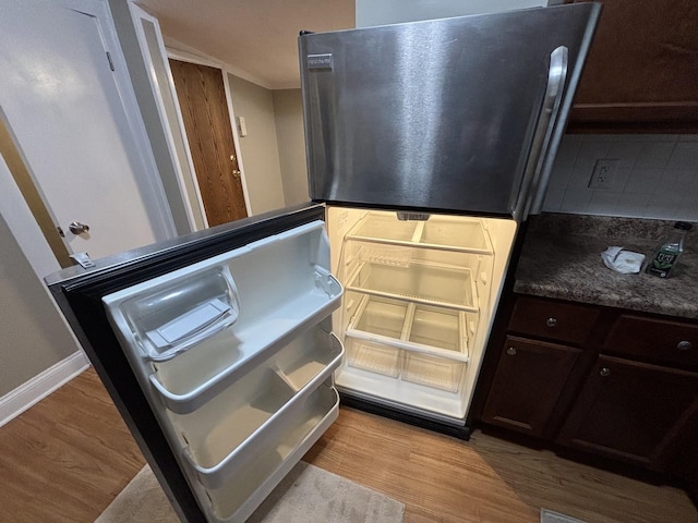 interior details with dark brown cabinets, decorative backsplash, stainless steel refrigerator, and light hardwood / wood-style flooring