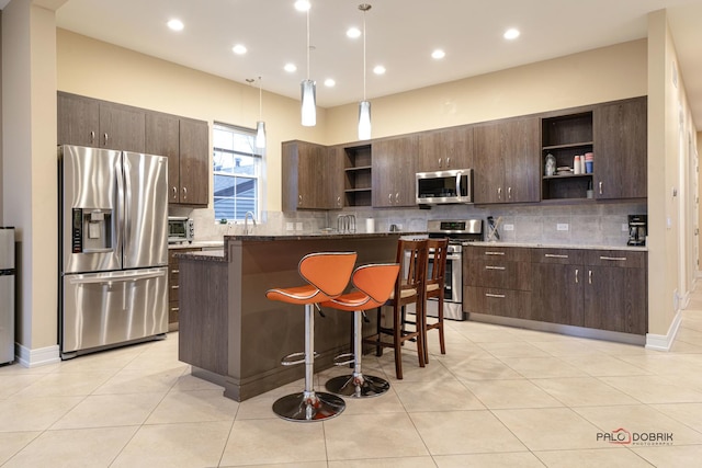 kitchen with dark brown cabinetry, a center island, light tile patterned floors, and stainless steel appliances