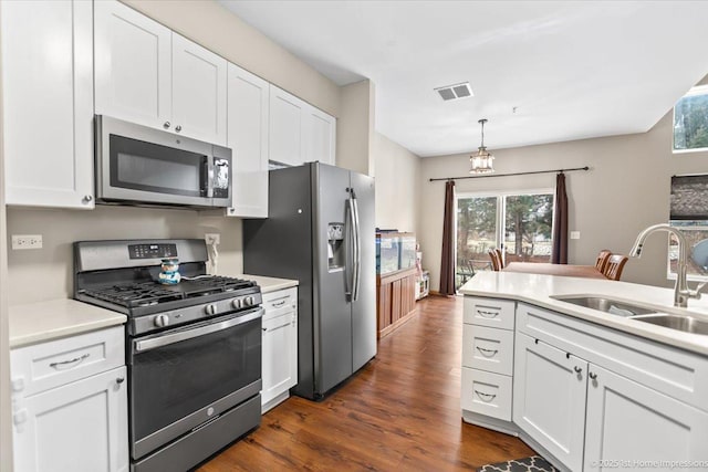 kitchen featuring dark hardwood / wood-style flooring, stainless steel appliances, sink, decorative light fixtures, and white cabinets