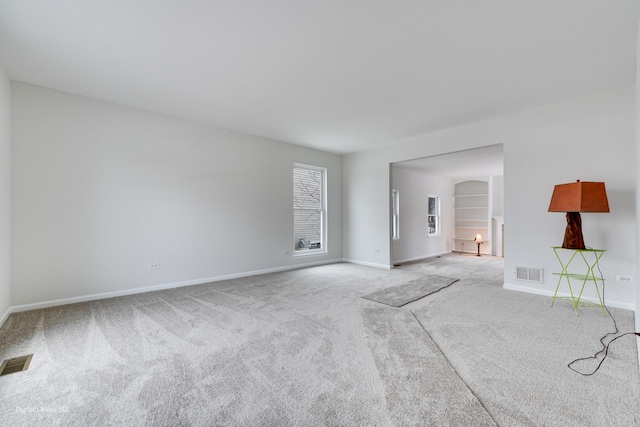 unfurnished living room featuring built in features and light colored carpet