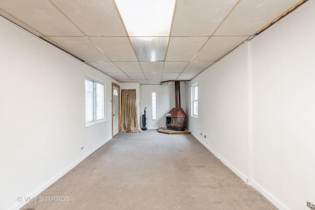 interior space featuring a paneled ceiling, light colored carpet, and a wood stove