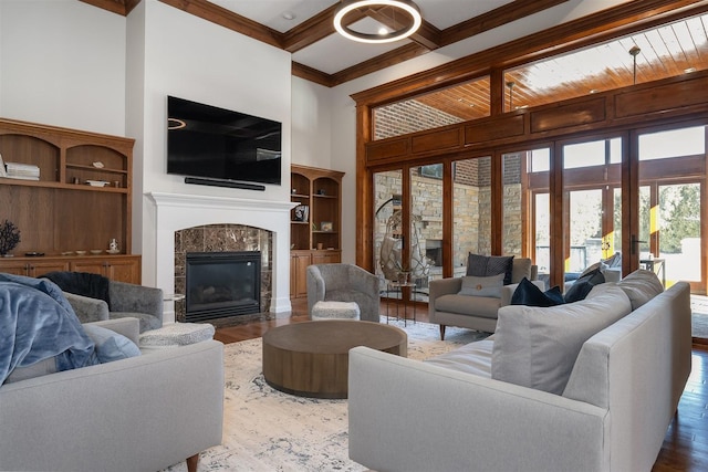 living room featuring beam ceiling, crown molding, hardwood / wood-style flooring, a fireplace, and a high ceiling