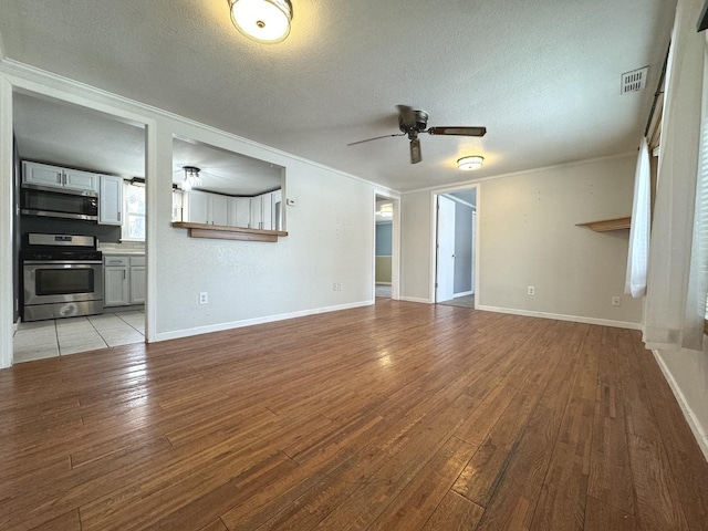 unfurnished living room featuring ceiling fan, light hardwood / wood-style floors, and a textured ceiling