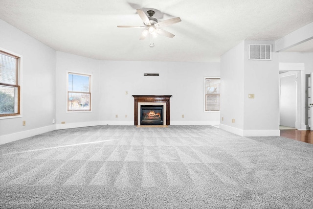 unfurnished living room with ceiling fan, light carpet, and a textured ceiling