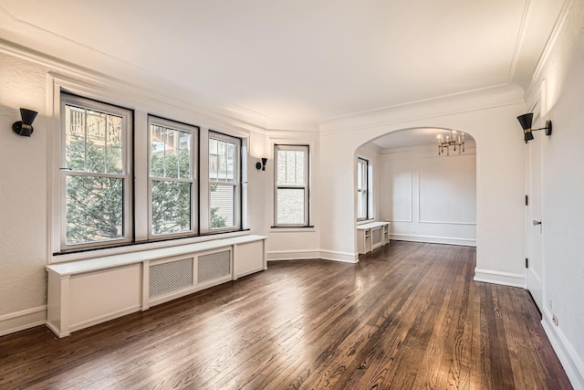 empty room with an inviting chandelier, crown molding, radiator heating unit, and dark hardwood / wood-style floors