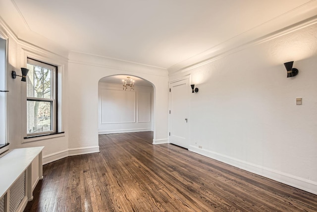 empty room with ornamental molding, dark hardwood / wood-style floors, and a notable chandelier