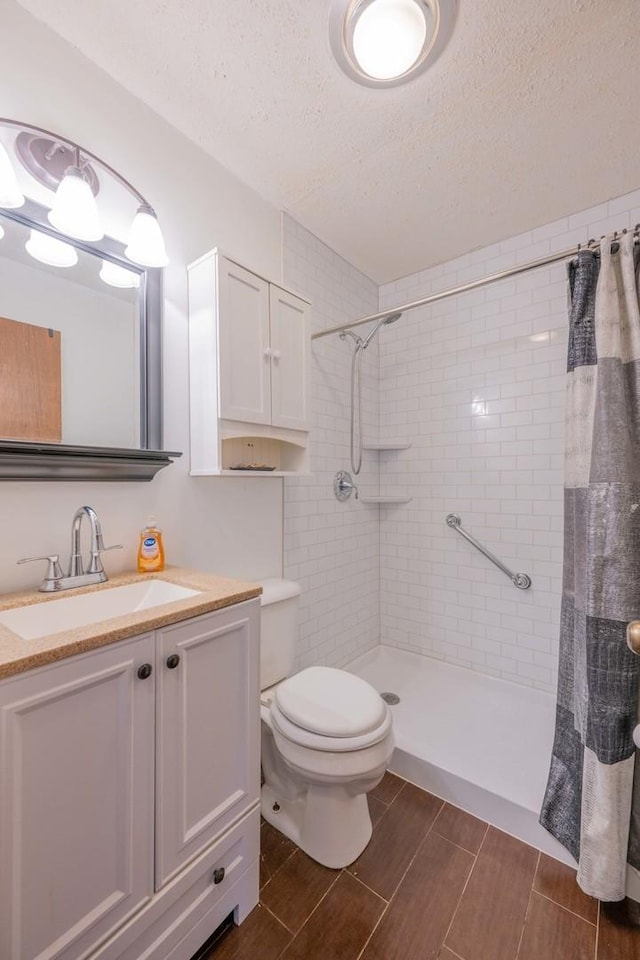 bathroom featuring a shower with shower curtain, toilet, a textured ceiling, and vanity