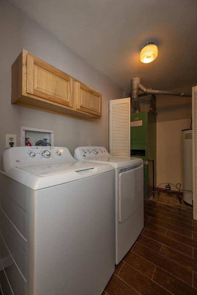 washroom with cabinets, washer and clothes dryer, and water heater