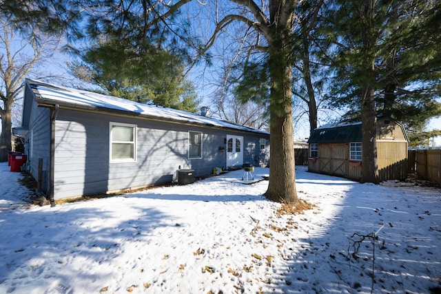 snow covered house featuring a storage unit