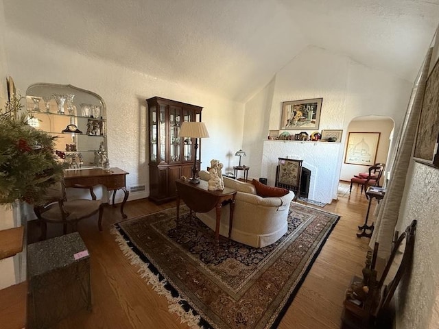 living room with a textured ceiling, vaulted ceiling, and wood-type flooring