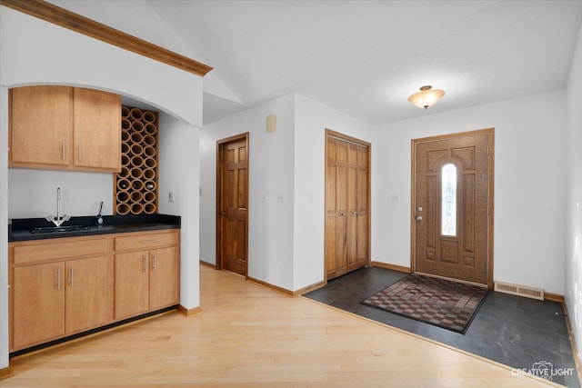 kitchen with lofted ceiling, sink, light brown cabinetry, and light hardwood / wood-style floors