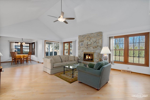 living room featuring high vaulted ceiling, a fireplace, light hardwood / wood-style floors, and ceiling fan