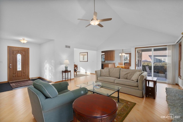 living room with plenty of natural light, high vaulted ceiling, ceiling fan, and light hardwood / wood-style flooring