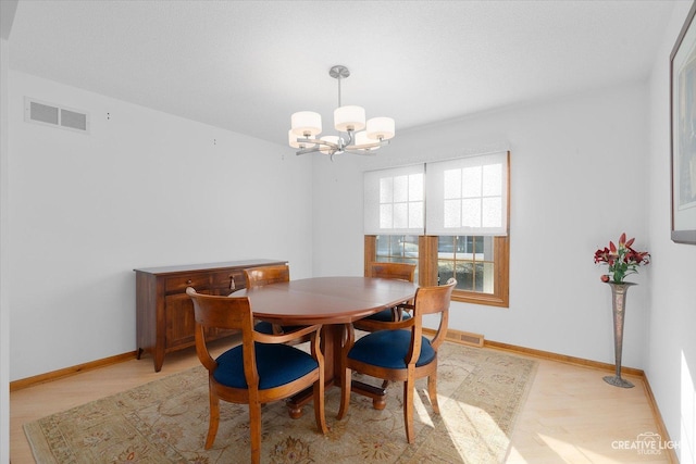 dining area featuring light hardwood / wood-style flooring and a chandelier