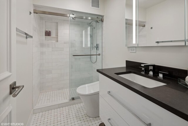 bathroom featuring vanity, a shower with shower door, and toilet