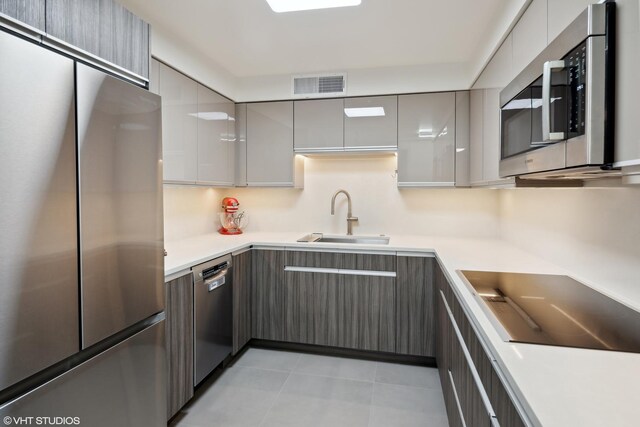 kitchen featuring light tile patterned floors, stainless steel appliances, gray cabinetry, and sink