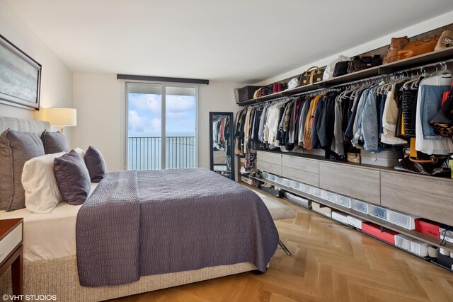 bedroom featuring access to outside, a closet, light parquet flooring, and a wall of windows