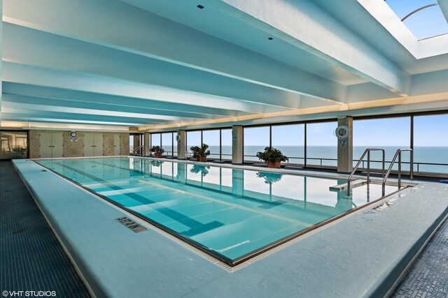 view of swimming pool featuring a water view and a skylight