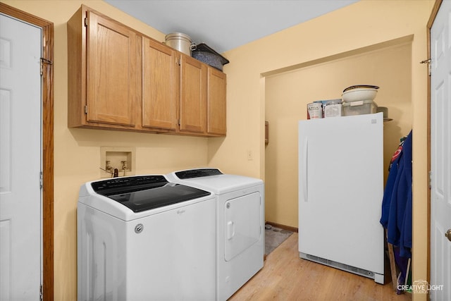 washroom featuring cabinets, light hardwood / wood-style floors, and washing machine and dryer