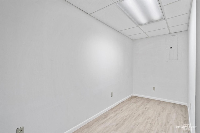 unfurnished room featuring a drop ceiling, light hardwood / wood-style floors, and electric panel