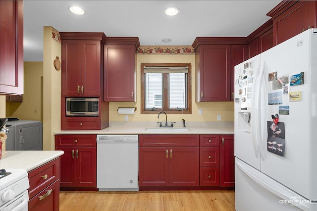 kitchen with washer and dryer, light hardwood / wood-style floors, white appliances, and sink