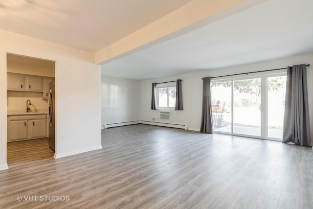 empty room with a baseboard heating unit, light hardwood / wood-style flooring, and sink