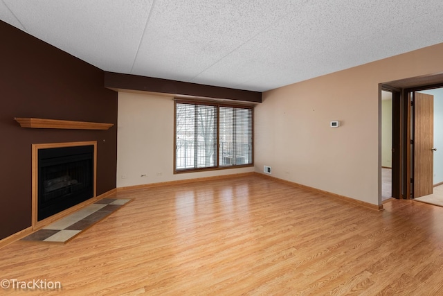 unfurnished living room with light hardwood / wood-style floors and a textured ceiling