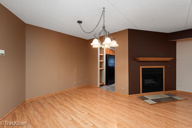 unfurnished living room with light hardwood / wood-style floors and an inviting chandelier