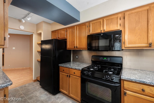 kitchen with track lighting, tasteful backsplash, black appliances, and light stone counters