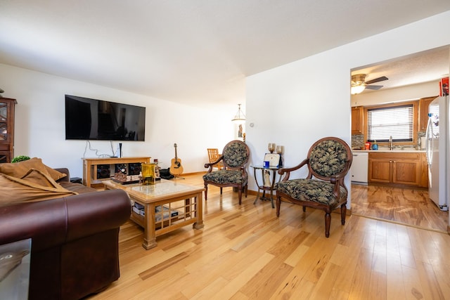 living room featuring sink, ceiling fan, and light hardwood / wood-style floors