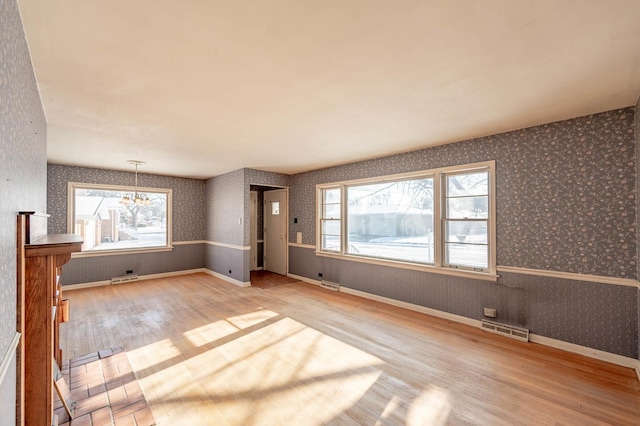 unfurnished living room with hardwood / wood-style flooring and a chandelier