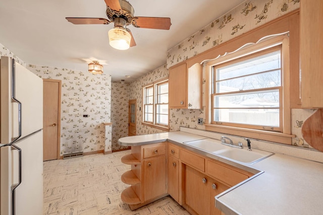 kitchen featuring plenty of natural light, white refrigerator, kitchen peninsula, and sink