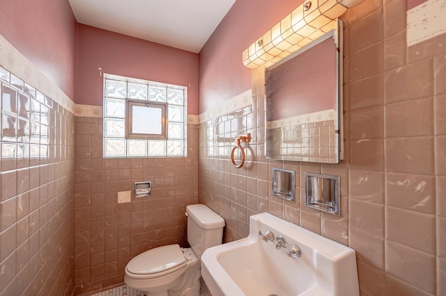 bathroom featuring toilet, sink, tile walls, and tile patterned flooring