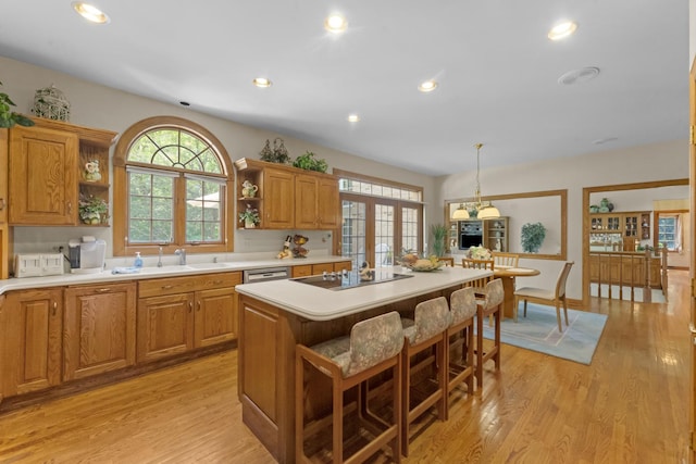 kitchen featuring decorative light fixtures, a center island, black electric cooktop, and a healthy amount of sunlight