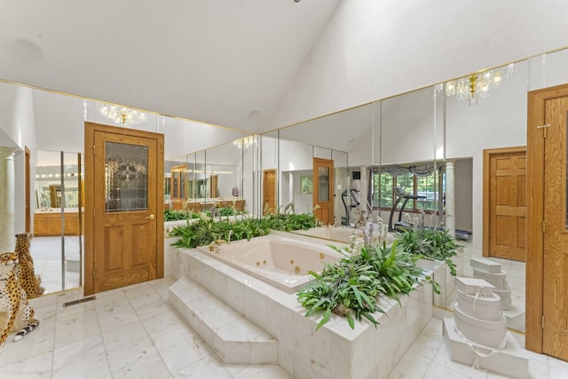 bathroom featuring a relaxing tiled tub and high vaulted ceiling