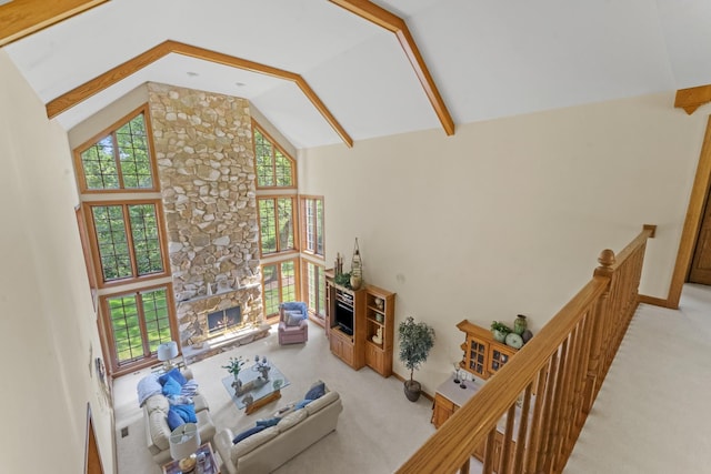 living room with a healthy amount of sunlight, a stone fireplace, light carpet, and high vaulted ceiling