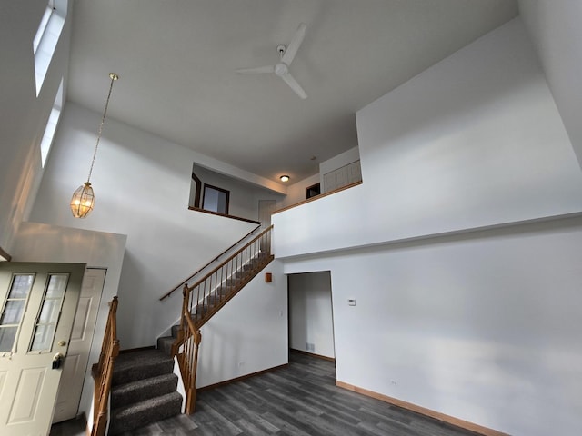 stairway with hardwood / wood-style flooring, ceiling fan, and a high ceiling