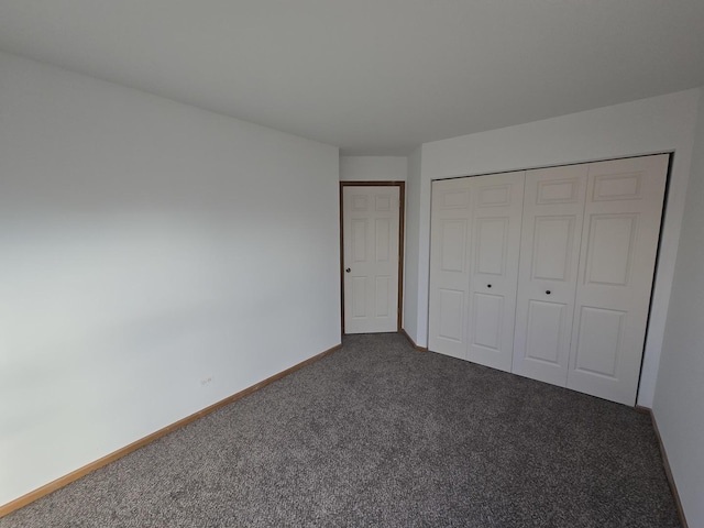 unfurnished bedroom featuring a closet and dark carpet