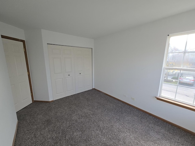 unfurnished bedroom featuring dark carpet and a closet