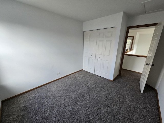 unfurnished bedroom featuring dark carpet and a closet