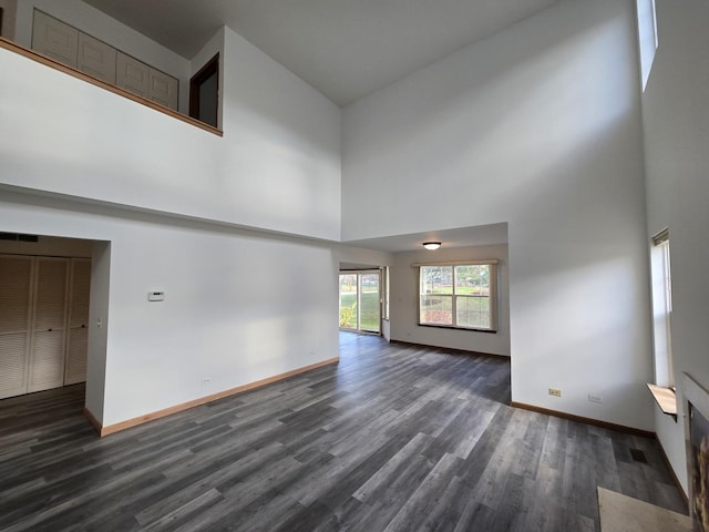 unfurnished living room featuring a high ceiling and dark hardwood / wood-style floors