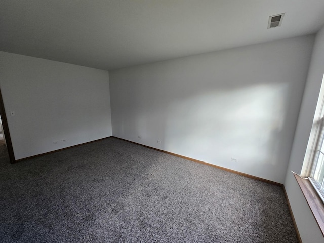 spare room featuring dark colored carpet