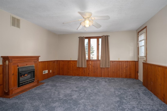 unfurnished living room featuring ceiling fan, carpet flooring, and a textured ceiling