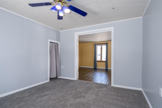 unfurnished room featuring dark colored carpet, ornamental molding, and ceiling fan