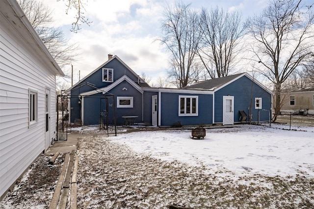 snow covered rear of property featuring an outdoor fire pit