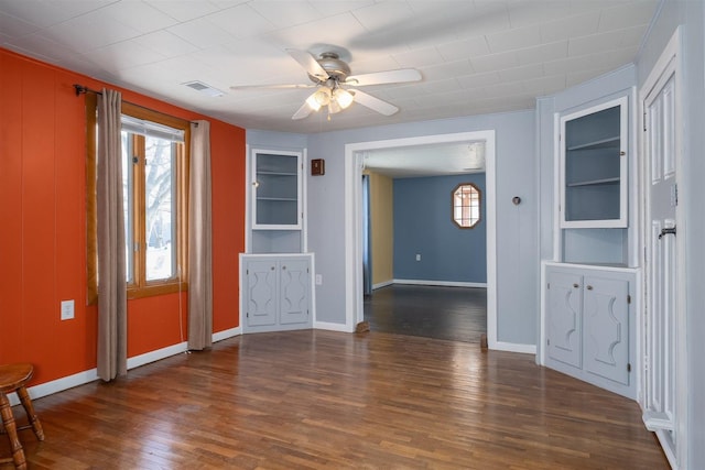 unfurnished room featuring dark wood-type flooring, built in features, and ceiling fan