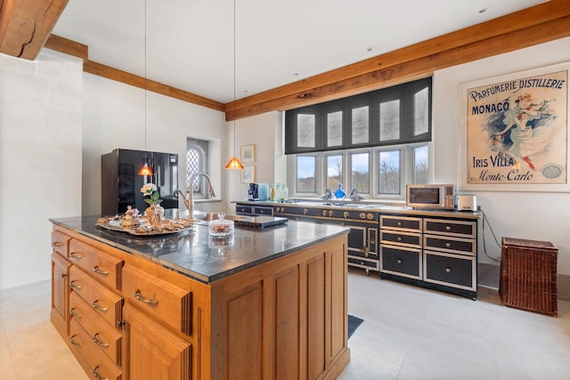 kitchen featuring sink, decorative light fixtures, dark stone countertops, and an island with sink