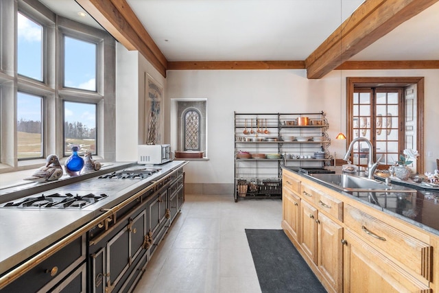 kitchen featuring light brown cabinetry, beam ceiling, stainless steel gas stovetop, and sink